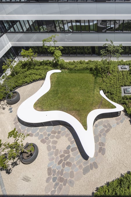 Organisch-geformte-Stehtresen-aus-weissem-Mineralwerkstoff-mit-Raseneinfassung-in-moderner-Aussenanlage