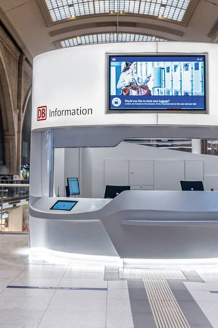 Informationstheke-der-Deutschen-Bahn-aus-weissem-Mineralwerkstoff-im-oeffentlichen-Raum