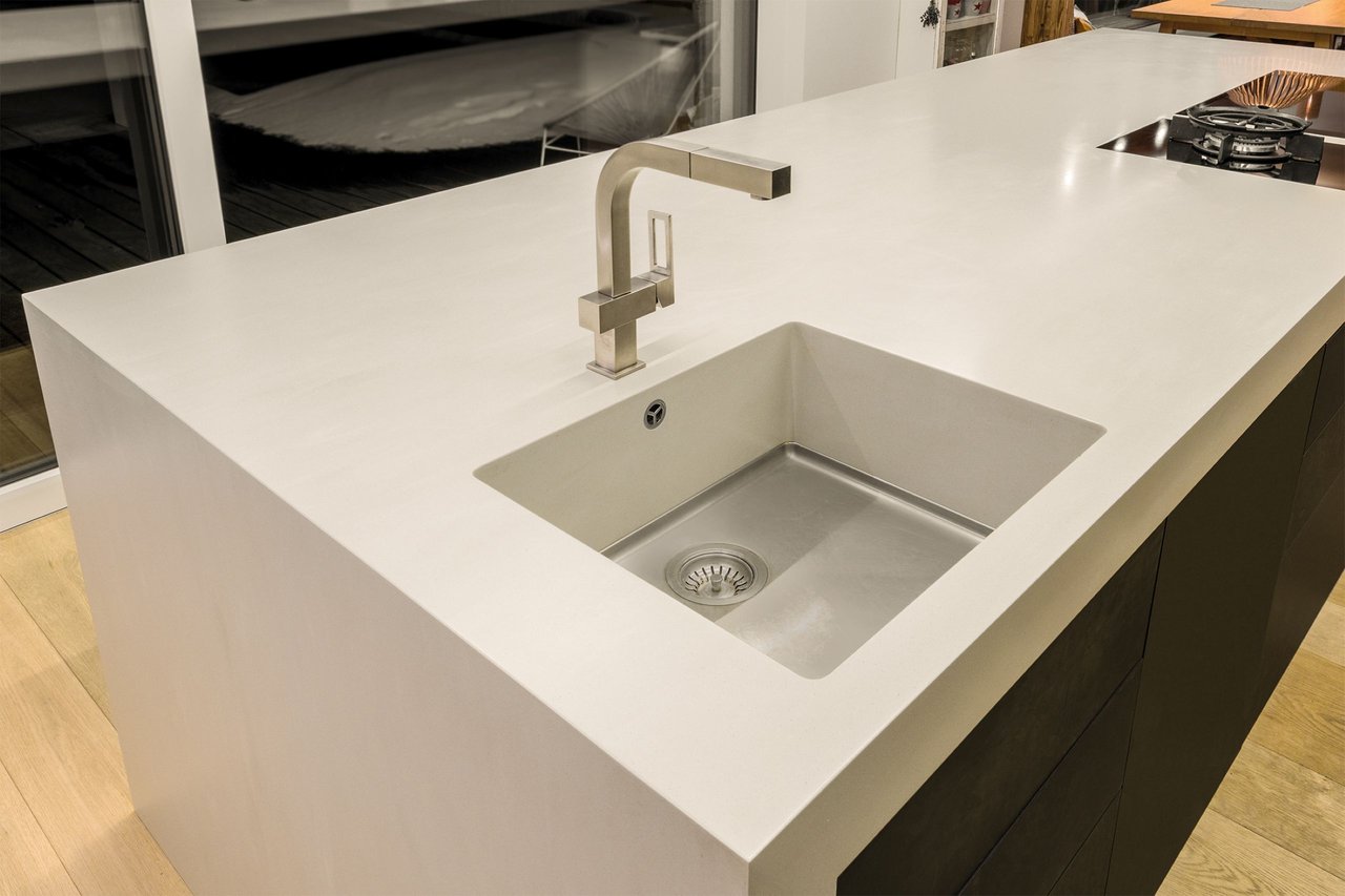 Kochinsel-mit-weisser-Mineralwerkstoff-Arbeitsplatte-und-nahtlos-eingelassener-Spuele