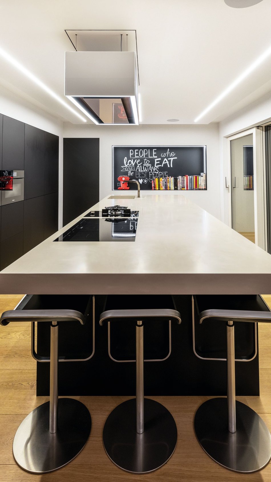 Frontales-Hochformat-der-schwarzen-Kueche-mit-langer-Insel-aus-Mineralwerkstoff-in-Betonoptik-von-Hasenkopf