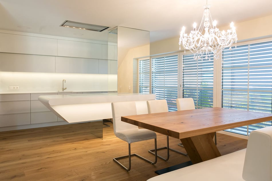 schwebende-kochsinsel-aus-weissem-Mineralwerkstoff-in-heller-Kueche-mit-Esstisch-aus-Holz