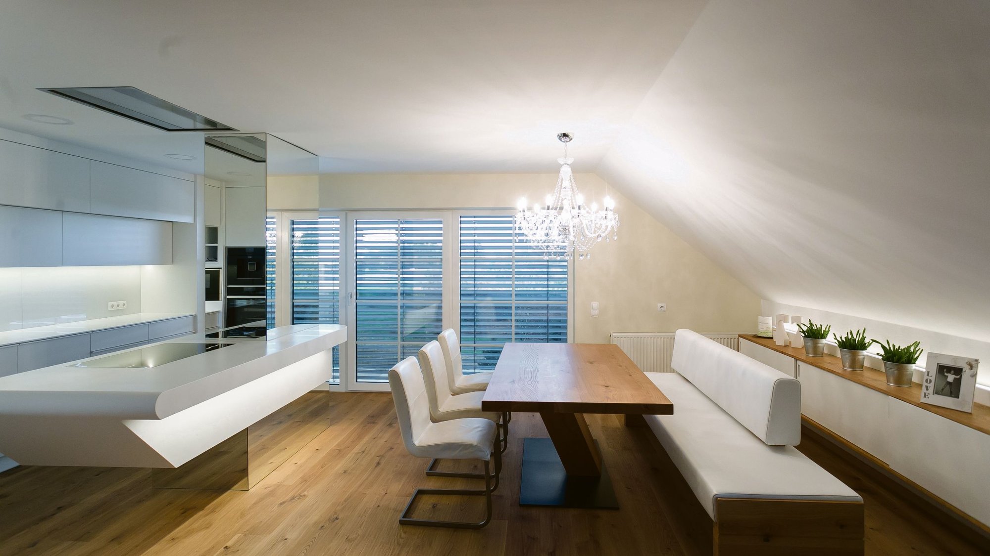 Gesamter-Essbereich-mit-weißer-Küche-aus-Corian-und-Sitzecke-mit-Holztisch-und-weißen-Lederstühlen Gesamter-Essbereich-mit-weißer-Küche-aus-Corian-und-Sitzecke-mit-Holztisch-und-weißen-Lederstühlen