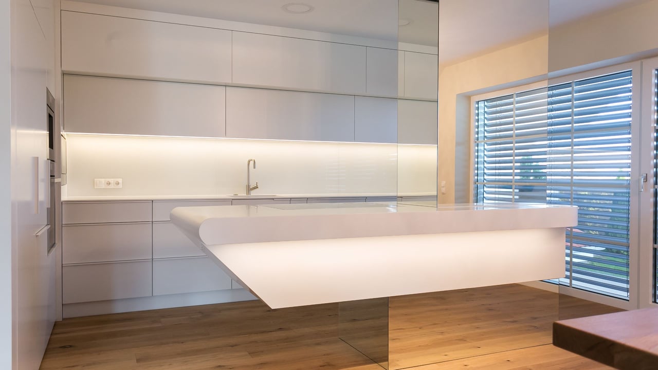 Weisse-Kueche-mit-schwebender-Corian-Kuecheninsel-gefertigt-von-Hasenkopf-vor-geschlossenen-Jalousien