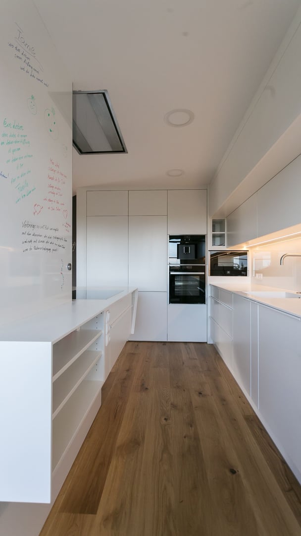 Hochformat-des-Kuechendurchgangs-mit-Corian-Oberflaechen-und-Whiteboard-mit-Schriftzuegen