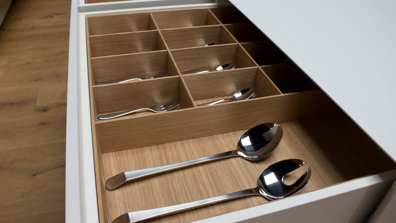 Detailansicht-einer-geoeffneten-Schublade-mit-Einteilung-aus-Eichenholz-fuer-Besteck