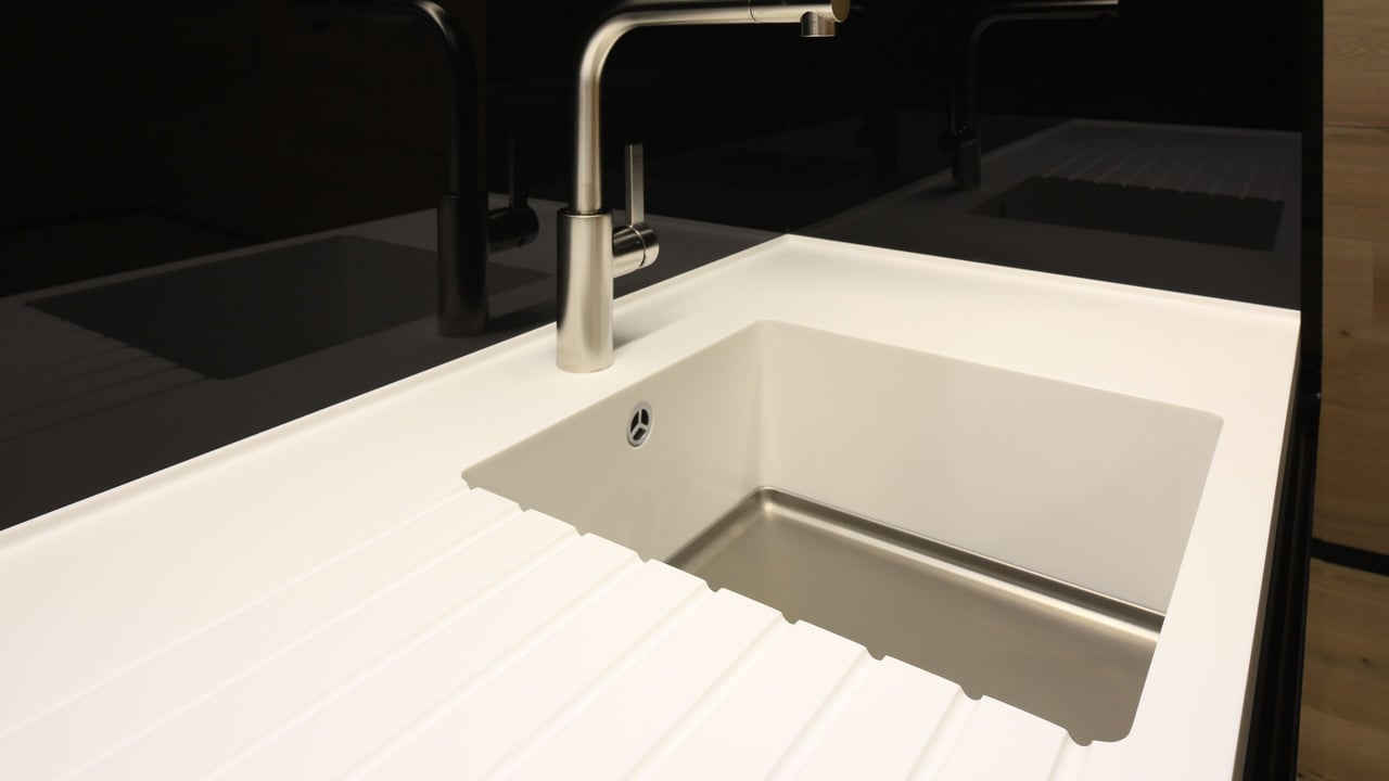 Nahaufnahme-des-fugenlosen-uebergangs-vom-weissen-Corian-Abtropfbereich-zur-Edelstahlspuele