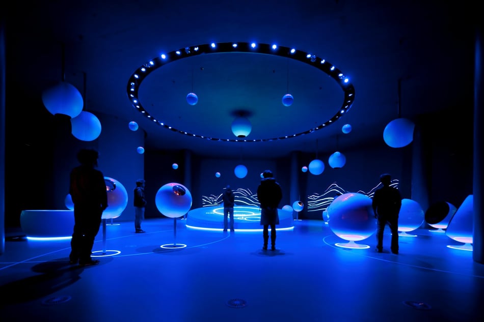 Universe-of-Particles-Cern-Ausstellung-mit-runden-Exponaten-aus-Mineralwerkstoff-und-blauer-Beleuchtung