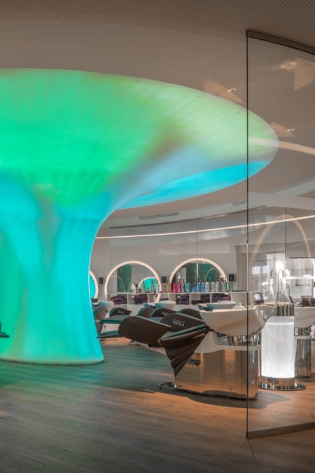 Beautysalon-mit-beleuchteter-pilzfoermiger-Lichtskulptur-aus-Mineralwerkstoff-und-runden-Spiegeln