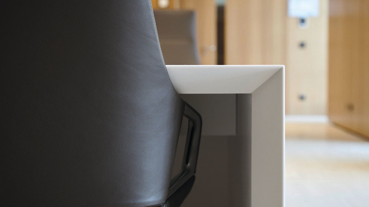 Detail des Corian-Konferenztisches kombiniert mit modernen Leder-Sitzmöbeln und vertäfelten Nussbaumwänden