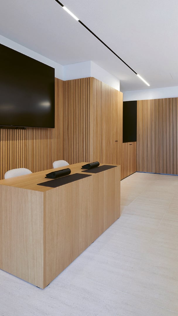 Detail des Sitzungssaals im Mamer Schlass: elegante Nussbaumfrontmöbel und integrierte Lichtbänder an der Decke Detail des Sitzungssaals im Mamer Schlass: elegante Nussbaumfrontmöbel und integrierte Lichtbänder an der Decke