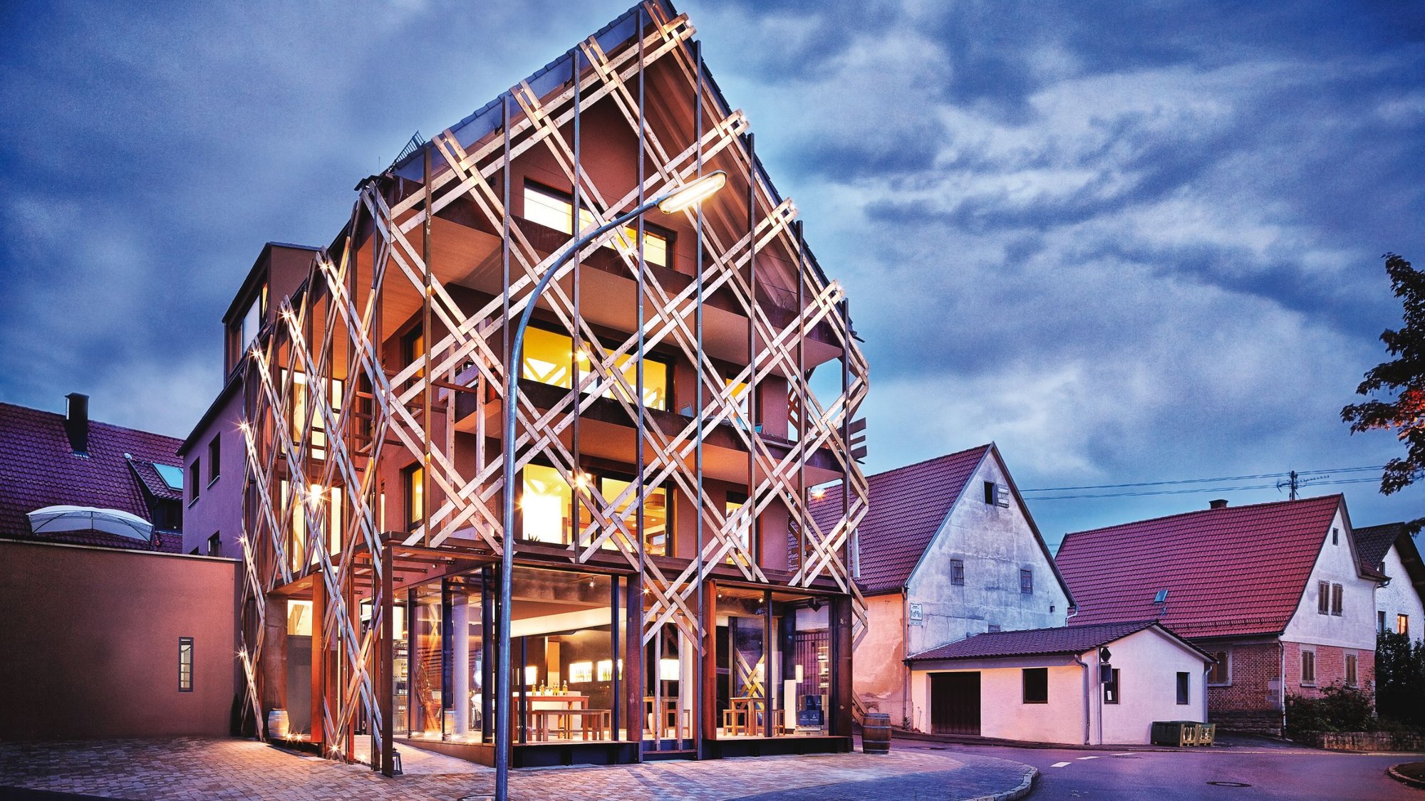 Außenaufnahme der Vinothek Weinkorb im Remstal mit charakteristischer Holzflechtstruktur bei Dämmerung Außenaufnahme der Vinothek Weinkorb im Remstal mit charakteristischer Holzflechtstruktur bei Dämmerung