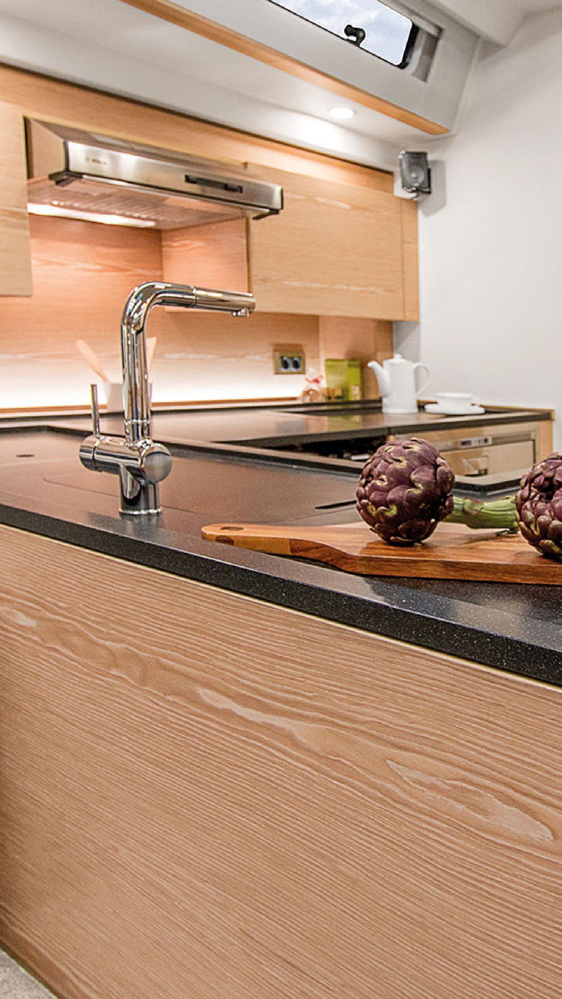 Moderne-Yachtküche-mit-schwarzer-Corian-Arbeitsfläche-und-Holzfronten-auf-HanseYacht Moderne-Yachtküche-mit-schwarzer-Corian-Arbeitsfläche-und-Holzfronten-auf-HanseYacht