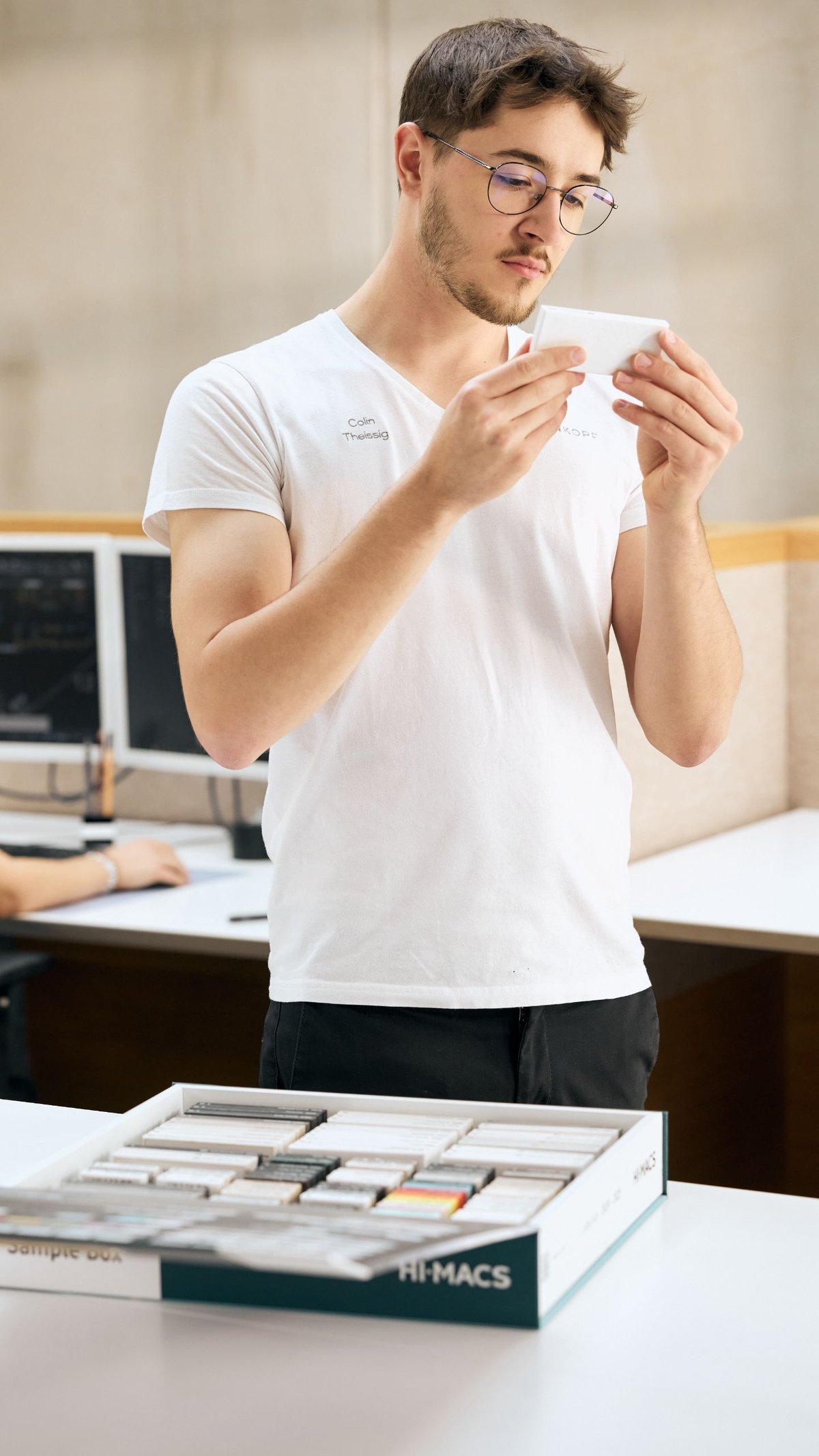Hasenkopf_Mitarbeiter_in_weissem_Brandshirt_schaut_sich_Materialproben_an