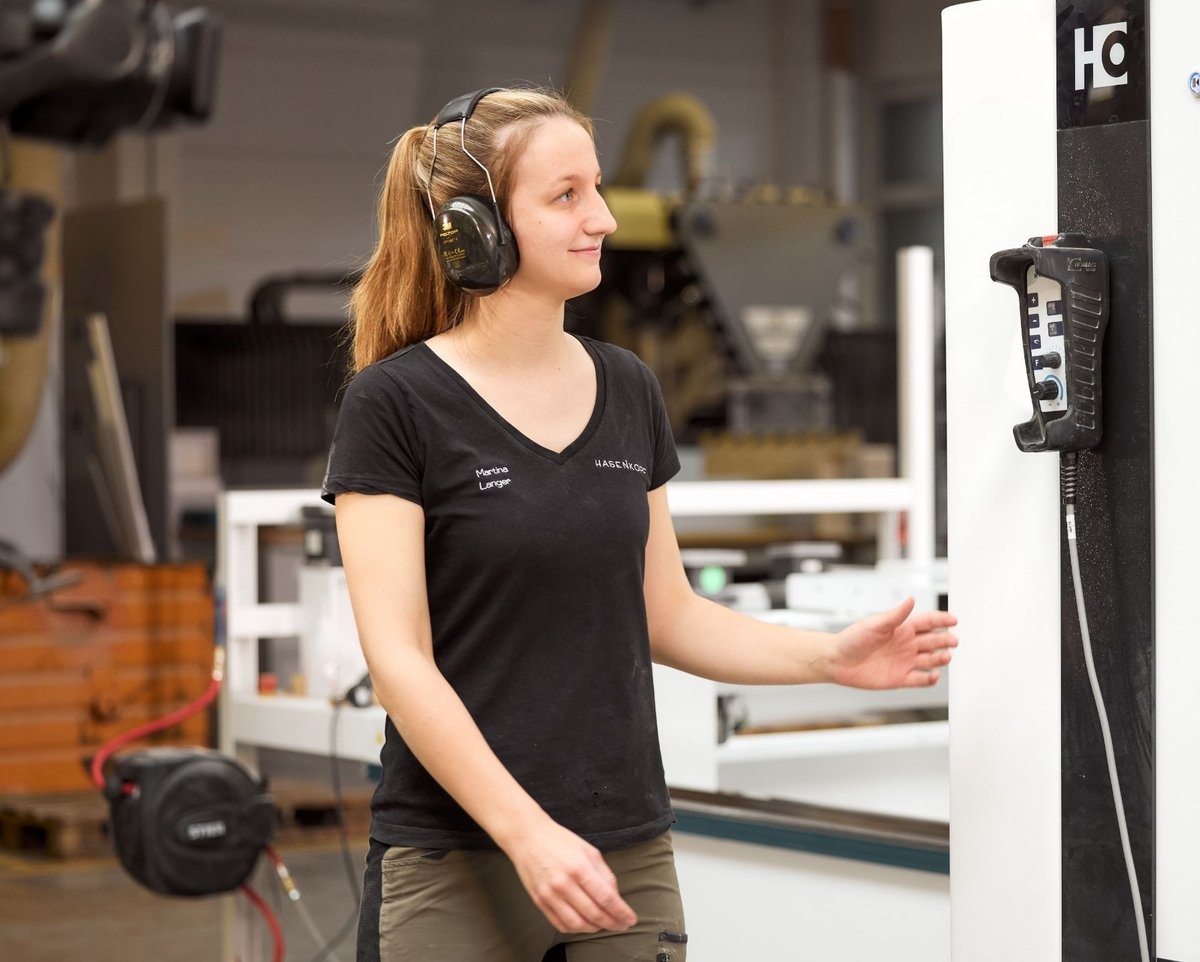 Hasenkopf_Mitarbeiterin_in_schwarzem_Brandshirt_und_Ohrenschutz_in_der_Produktion