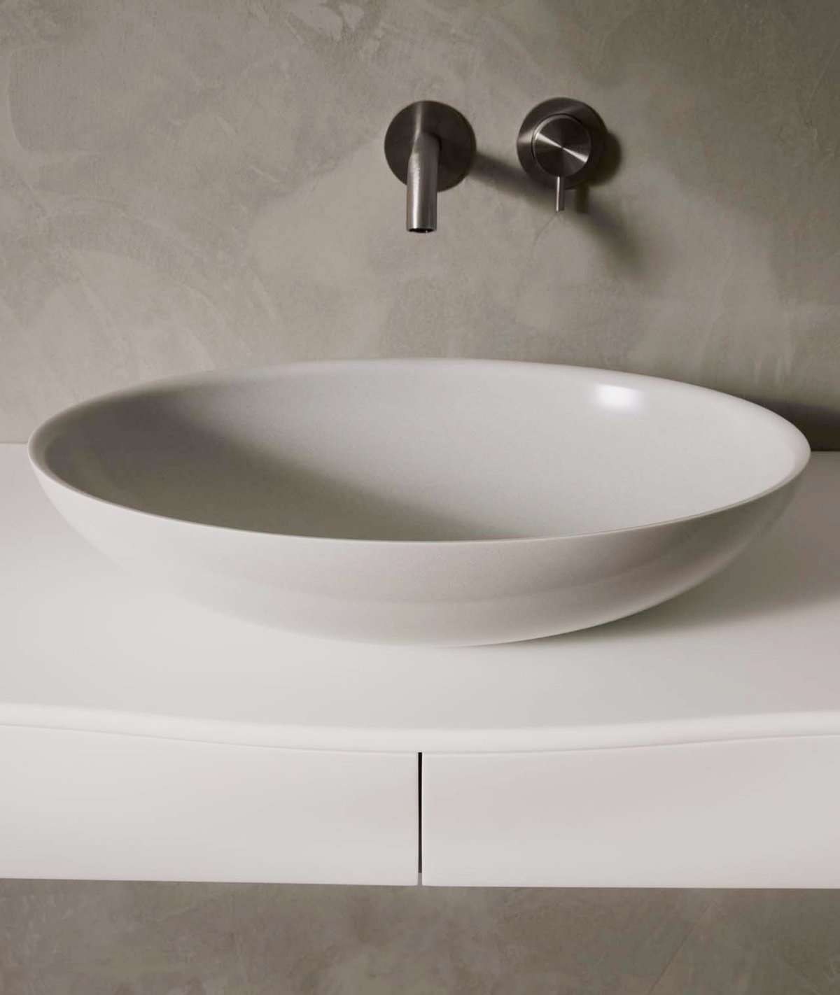 weißes-aufsatzbecken-aus-mineralwerkstoff-mit-silbernen-wasserhähnen