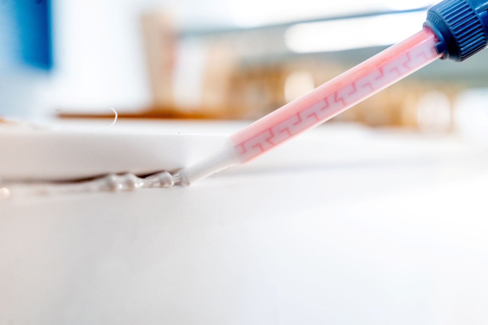 Auftragen-von-Kleber-auf-eine-Mineralwerkstofffläche-mit-einer-Dosierspitze Auftragen-von-Kleber-auf-eine-Mineralwerkstofffläche-mit-einer-Dosierspitze