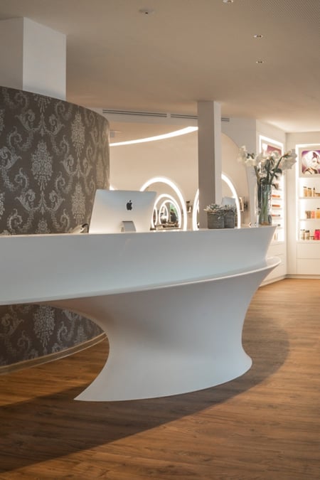 Elegante-Theke-aus-weißem-Mineralwerkstoff-im-Beautysalon-Egger