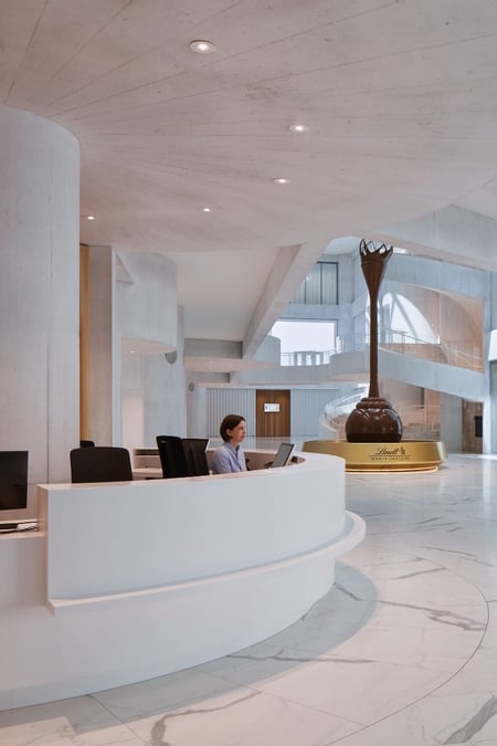 Empfangstheke-aus-Mineralwerkstoff-im-Lindt-Home-of-Chocolate-mit-organisch-runder-Form