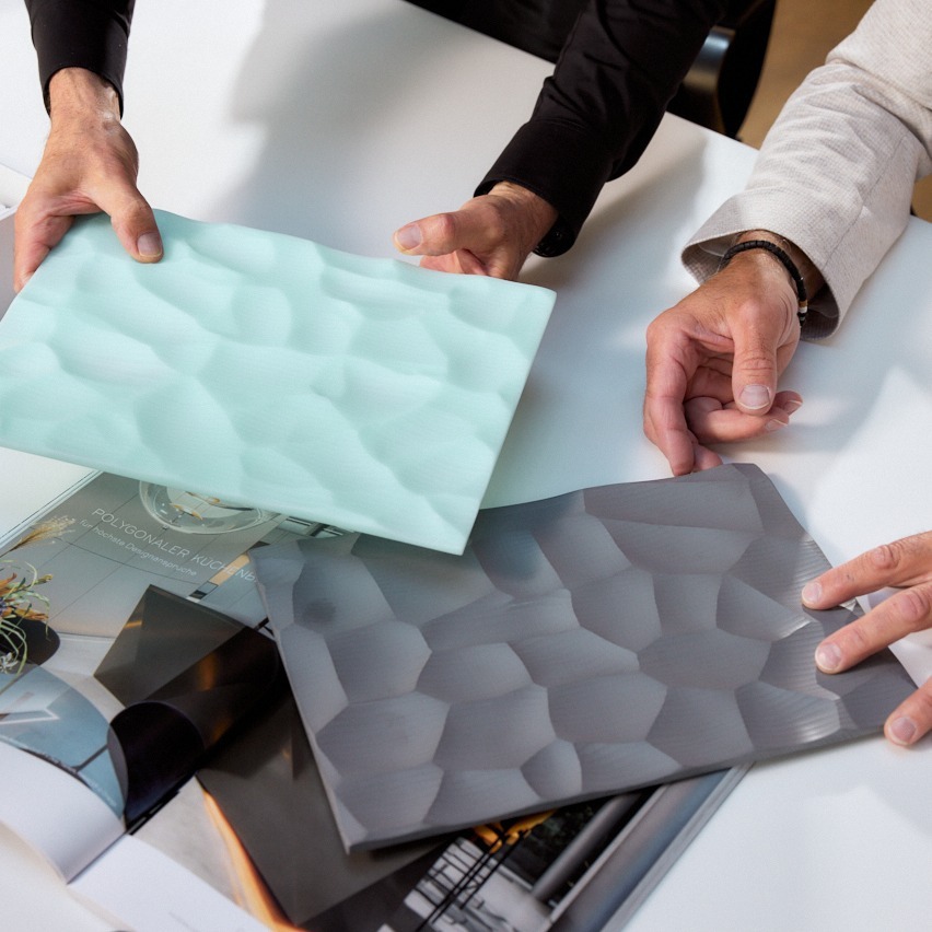 Hände zeigen unterschiedliche Materialmuster von Mineralwerkstoff in Frescata Fräsung